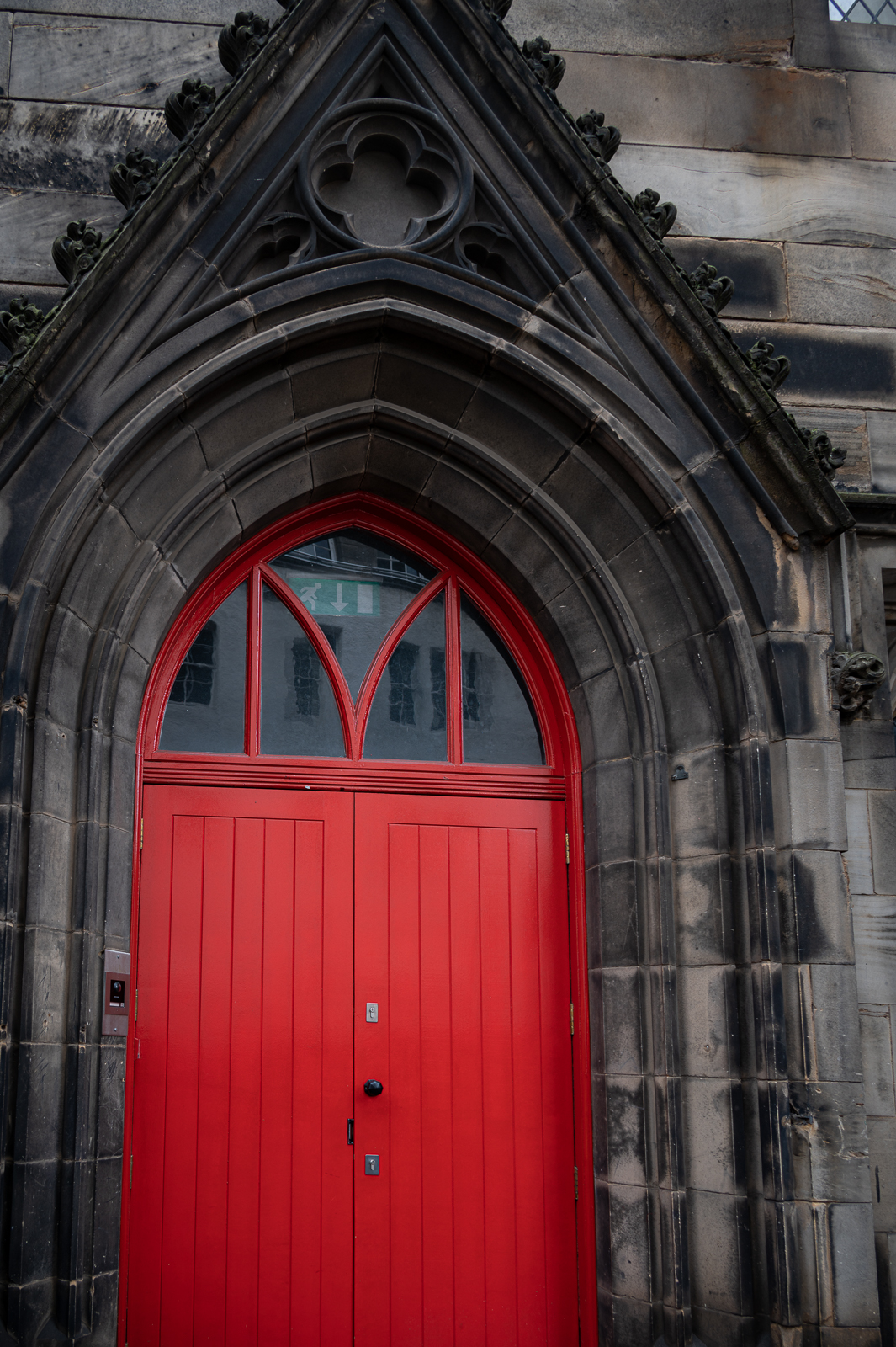 Arched red door with weathered stone gable.